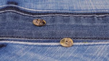 Natural mother of pearl buttons fall on denim. Slow motion.