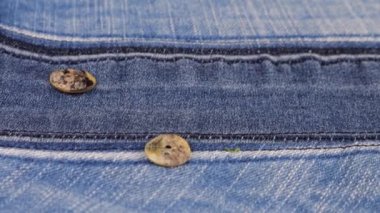 Natural mother of pearl buttons fall on denim. Slow motion.