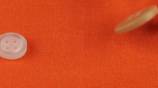 彩色塑料纽扣落在橙色棉织物上 — 图库视频影像