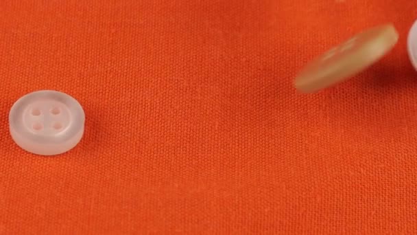 Пластиковые Разноцветные Пуговицы Падают Оранжевую Хлопковую Ткань — стоковое видео