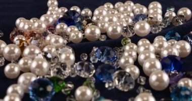 Transparent white and multi-colored jewelry crystals, rhinestones and pearls on blue velvet.