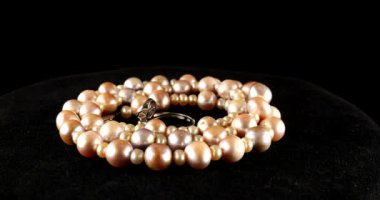 Necklace and silver ring made of natural sea pearls on black velvet.