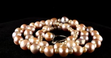 Necklace and silver ring made of natural sea pearls on black velvet.