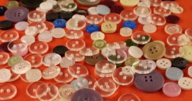 Plastic multi-colored buttons on an orange cotton fabric.