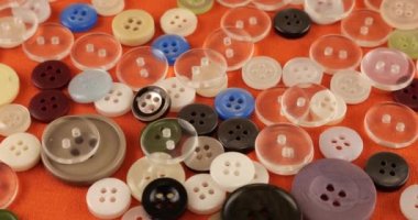 Plastic multi-colored buttons on an orange cotton fabric.