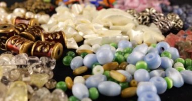 Beads made of chrysoberyl, cymophane, cats eye, natural mother of pearl, colored glass, rhinestone, smoky quartz, quartz, turquoise, natural pearls, metal, ceramics and copper on black velvet.