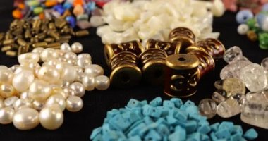 Beads made of chrysoberyl, cymophane, cats eye, natural mother of pearl, colored glass, rhinestone, smoky quartz, quartz, turquoise, natural pearls, metal, ceramics and copper on black velvet.