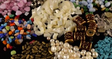 Beads made of chrysoberyl, cymophane, cats eye, natural mother of pearl, colored glass, rhinestone, smoky quartz, quartz, turquoise, natural pearls, metal, ceramics and copper on black velvet.