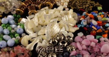 Beads made of chrysoberyl, cymophane, cats eye, natural mother of pearl, colored glass, rhinestone, smoky quartz, quartz, turquoise, natural pearls, metal, ceramics and copper on black velvet.