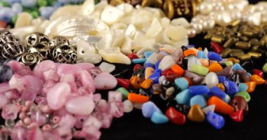 Beads made of chrysoberyl, cymophane, cats eye, natural mother of pearl, colored glass, rhinestone, smoky quartz, quartz, turquoise, natural pearls, metal, ceramics and copper on black velvet.