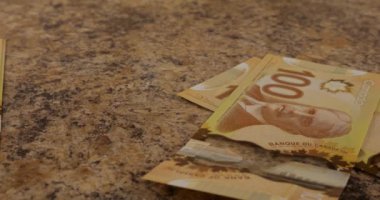 Falling Canadian 100 dollar polymer banknotes with a portrait of Robert Borden. Slow motion.