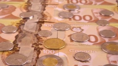 Canadian coins and 100 dollar polymer banknotes with a portrait of Robert Borden.