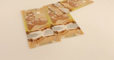 Falling Canadian 100 dollar polymer banknotes with a portrait of Robert Borden.