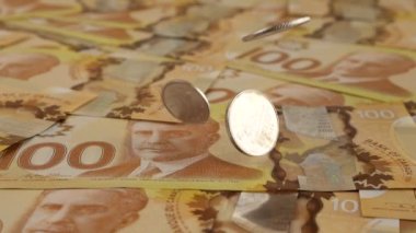 Falling Canadian coins on 100 dollar polymer banknotes with a portrait of Robert Borden. Slow motion.