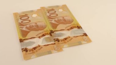 Falling Canadian 100 dollar polymer banknotes with a portrait of Robert Borden.