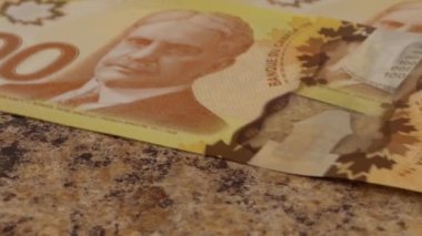 Falling Canadian 100 dollar polymer banknotes with a portrait of Robert Borden. Slow motion.