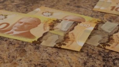 Falling Canadian 100 dollar polymer banknotes with a portrait of Robert Borden. Slow motion.