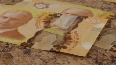 Falling Canadian 100 dollar polymer banknotes with a portrait of Robert Borden. Slow motion.