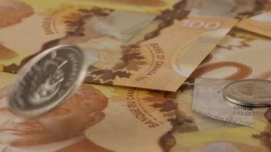 Falling Canadian coins on 100 dollar polymer banknotes with a portrait of Robert Borden. Slow motion.