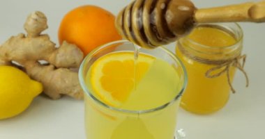 Cooking a drink made from citrus, ginger and honey to boost immunity. Honey is poured into a glass with a drink.