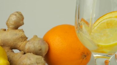 Cooking a drink made from citrus, ginger and honey to boost immunity. Lemonade is poured into a glass with slices of orange, lemon and ginger.