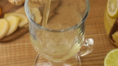 Cooking a drink of citrus and ginger to boost immunity. Lemonade is poured into a glass against the background of slices of orange, lemon, lime, ginger and a glass jug of lemonade.