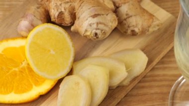 Cooking a drink of citrus and ginger to boost immunity. Lemonade is poured into a glass against the background of slices of orange, lemon and ginger. Slow motion.