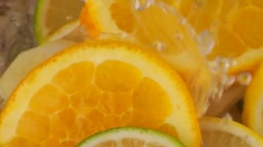Cooking lemonade from citrus, lemon, orange, lime and ginger. Hot water is poured into a glass container. Slow motion.