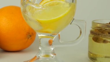 Cooking a drink made from citrus, ginger and honey to boost immunity. Lemonade is poured into a glass with slices of orange, lemon and ginger.