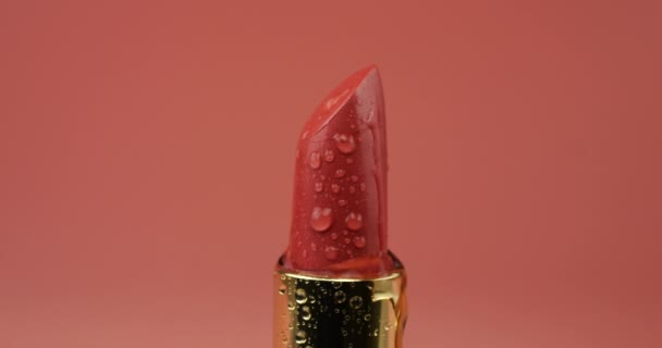 Rode Lippenstift Buis Met Water Druppels Geïsoleerd Een Roze Achtergrond — Stockvideo