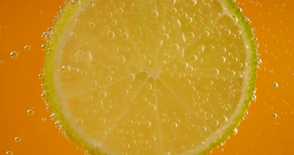 オレンジの背景に気泡の熟した石灰のスライス — ストック動画