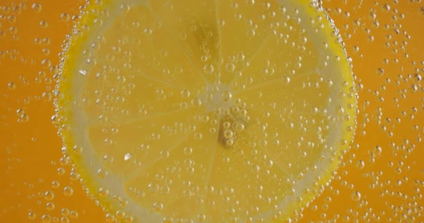 Slice Ripe Lemon Air Bubbles Orange Background — Stockvideo
