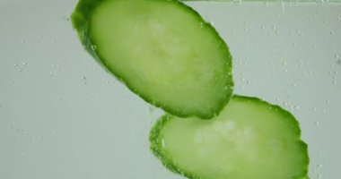 Falling fresh cucumber slices in air bubbles.