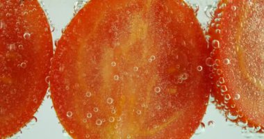 Ripe tomato in clear water with air bubbles.