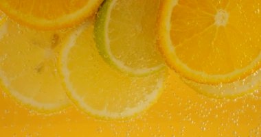 Ripe citrus lemonade, orange, lemon, lime slices in air bubbles.