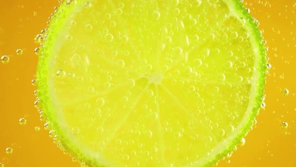 Eine Scheibe Reife Limette Luftblasen Auf Orangefarbenem Hintergrund — Stockvideo
