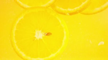 Falling ripe slices of lemon and orange on an orange background in air bubbles.