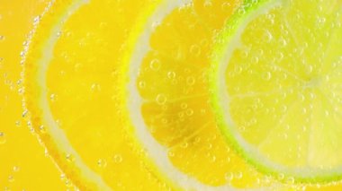 Ripe citrus lemonade, orange, lemon, lime slices in air bubbles.