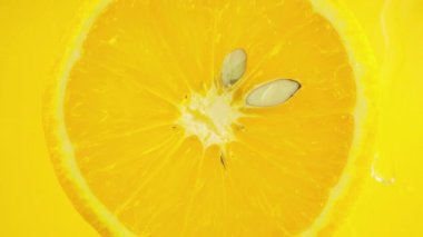 A slice of ripe orange in water bubbles on an orange background.