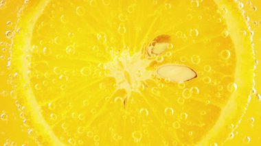 A slice of ripe orange in water bubbles on an orange background.