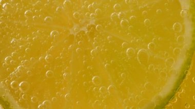 Ripe lime slices in air bubbles on an orange background.