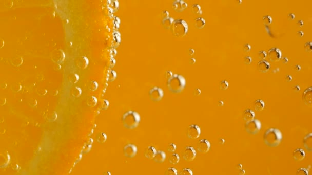 Кусок Спелого Апельсина Пузырьках Воды Оранжевом Фоне — стоковое видео