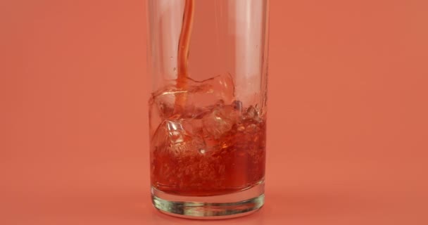 Granaatappelsap Wordt Gegoten Glazen Bekers Met Ijs Een Roze Achtergrond — Stockvideo
