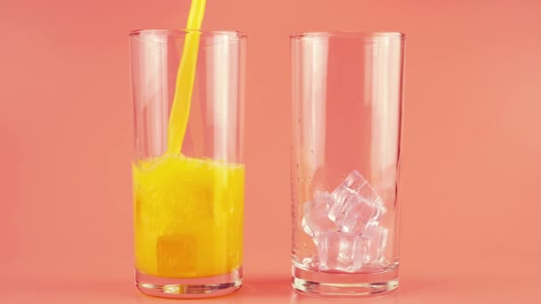 Апельсиновый Сок Наливают Стеклянные Чашки Льдом Розовом Фоне Медленное Движение — стоковое видео