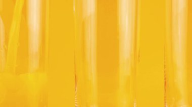 Portakal suyu portakal arkaplanındaki cam kadehlere dökülür. Yavaş çekim.