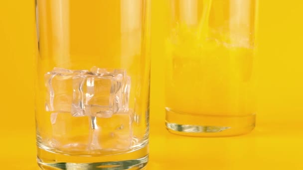 Sok Pomarańczowy Wlewa Się Szklanych Pucharów Lodem Pomarańczowym Tle Zwolniony — Wideo stockowe