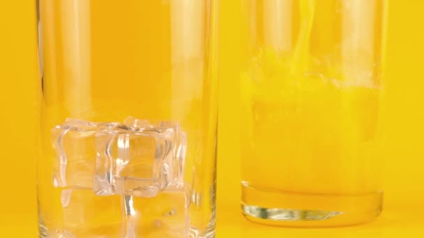 Sinaasappelsap Wordt Gegoten Glazen Bekers Met Ijs Een Oranje Achtergrond — Stockvideo