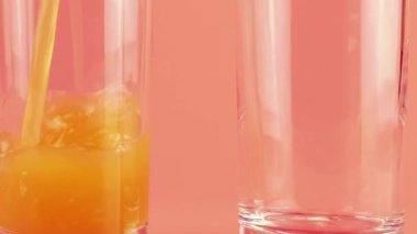 Elma suyu pembe arka planda cam kadehlere dökülür. Yavaş çekim.