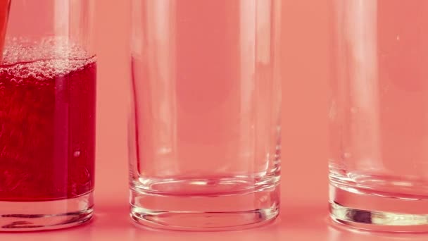 Sok Granatu Wlewa Się Szklanych Pucharów Różowym Tle Zwolniony Ruch — Wideo stockowe