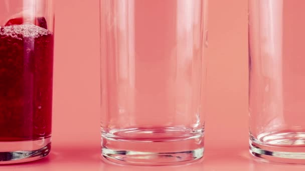 ピンクの背景にガラスのゴブレットにザクロジュースを注ぎます スローモーション — ストック動画